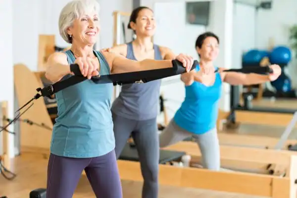 Toning Arms After 60: Empowering Womens Fitness Through Effective Weight Training 2 older woman doing weight training Scotland and resistance in the gym to tone upper arms